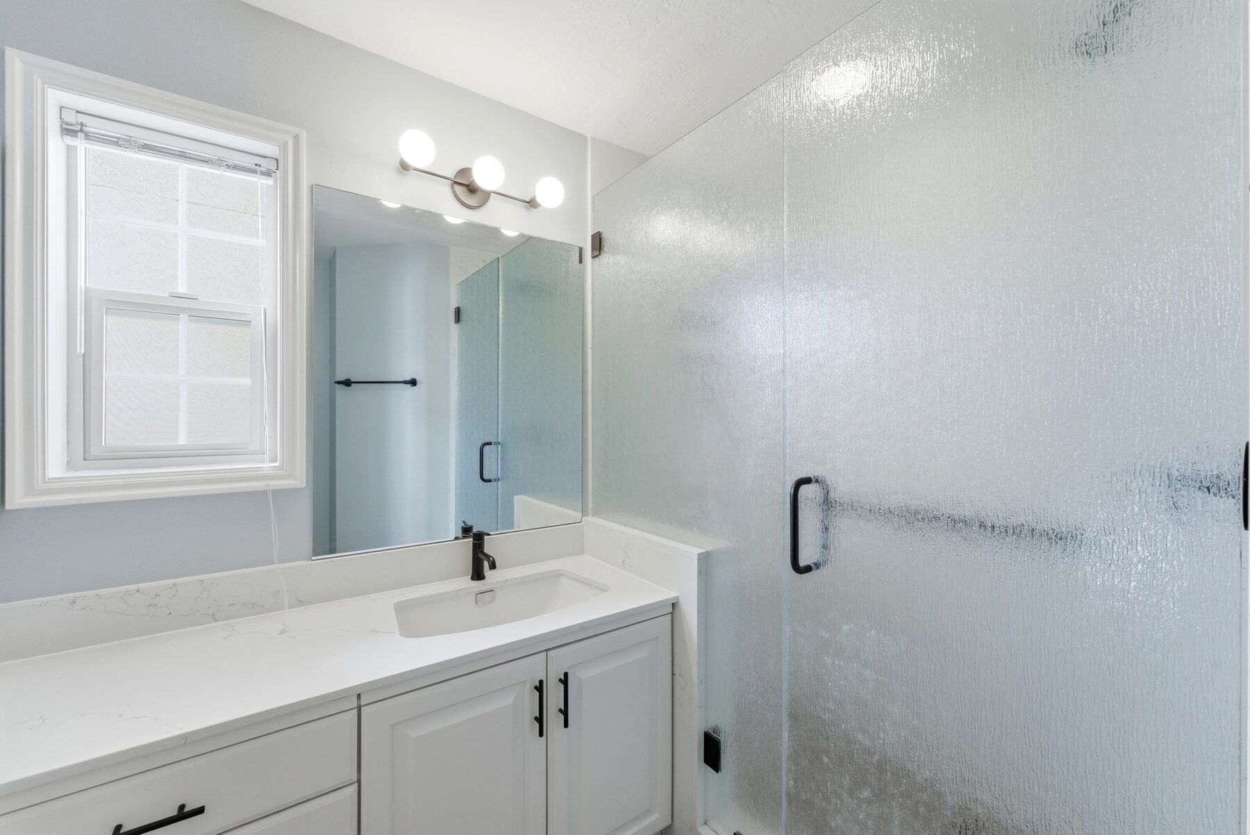 Updated bathroom with vanity and glass shower in remodeled Swiss Oaks condo Midway
