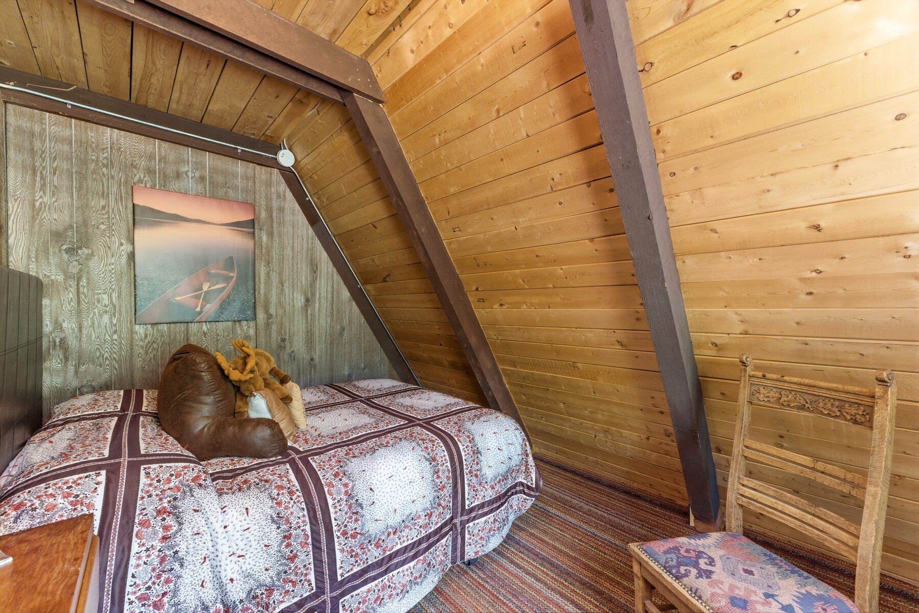 Cozy bedroom under the sloped A-frame ceiling in Timber Lakes cabin Heber City