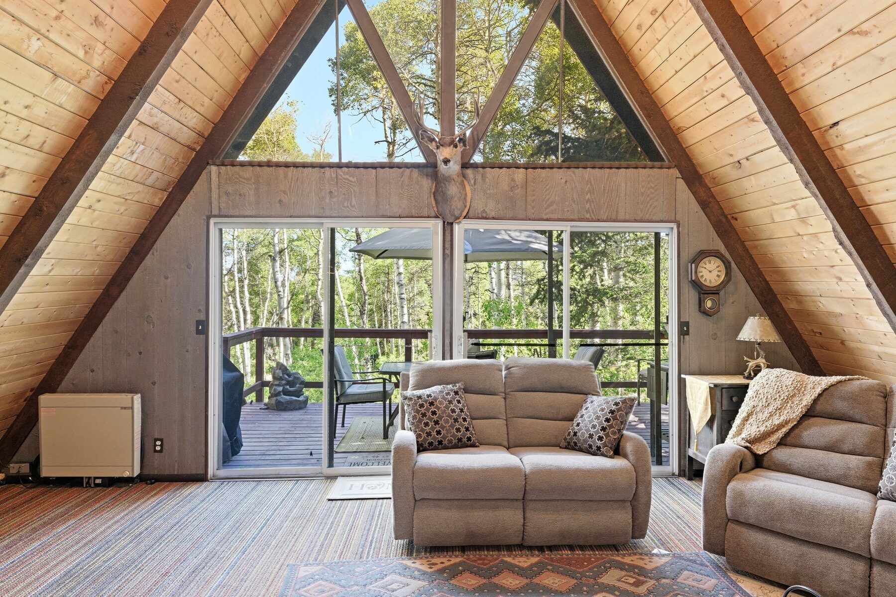 A-frame cabin interior with floor-to-ceiling windows framing the wooded acreage